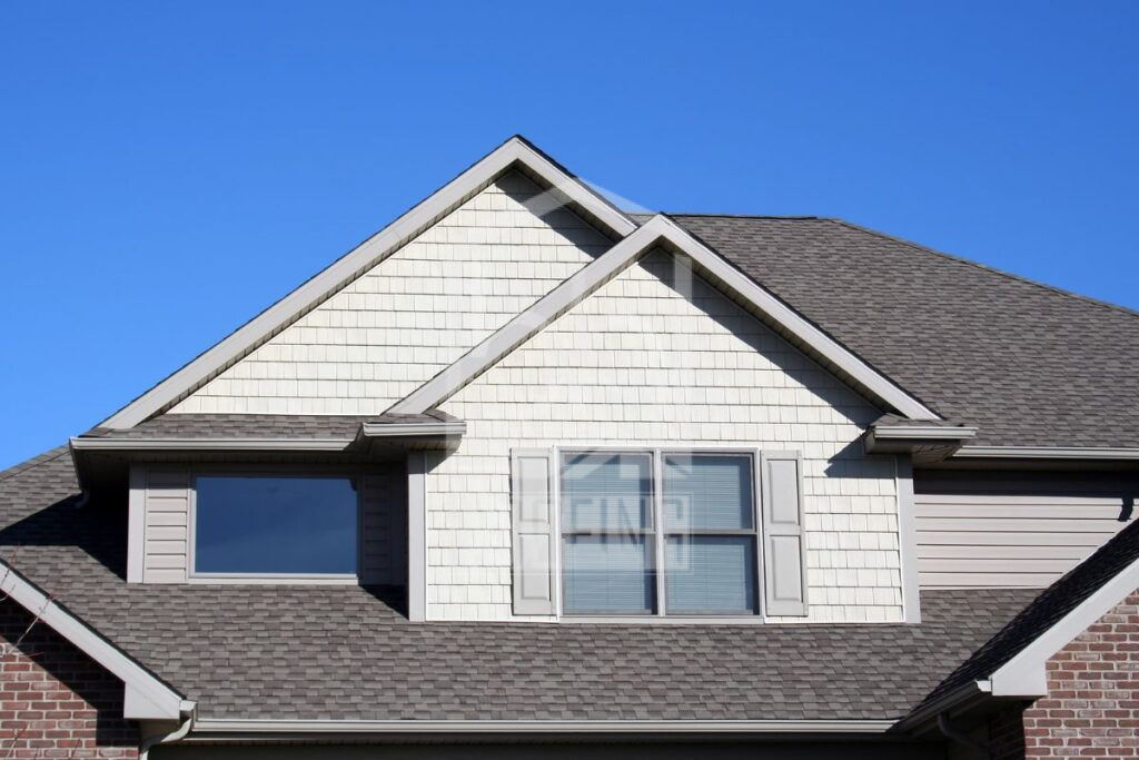 Close-up of a suburban house's attic with gabled roof under clear blue sky.