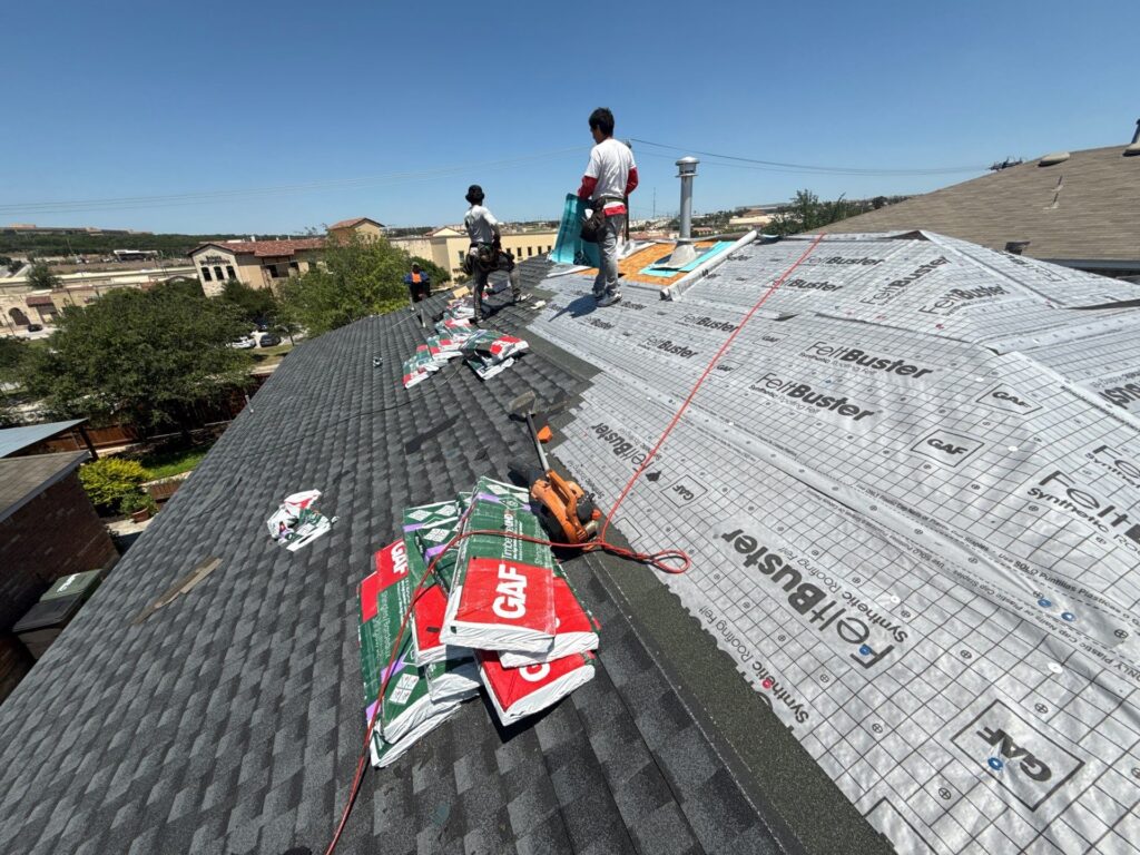 Workers installing roofing materials on house